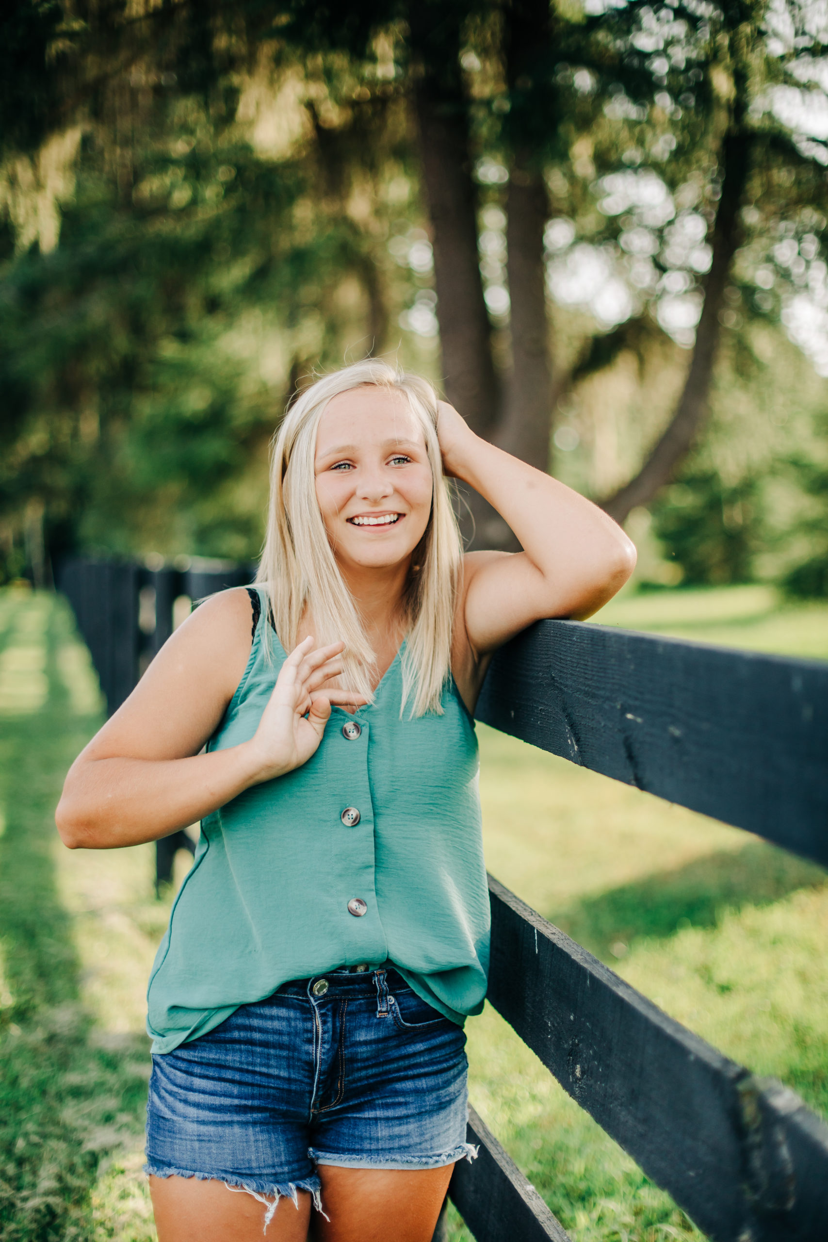 summer senior photos with girl leaning on a fence for outdoor senior pictures by Augusta photographers