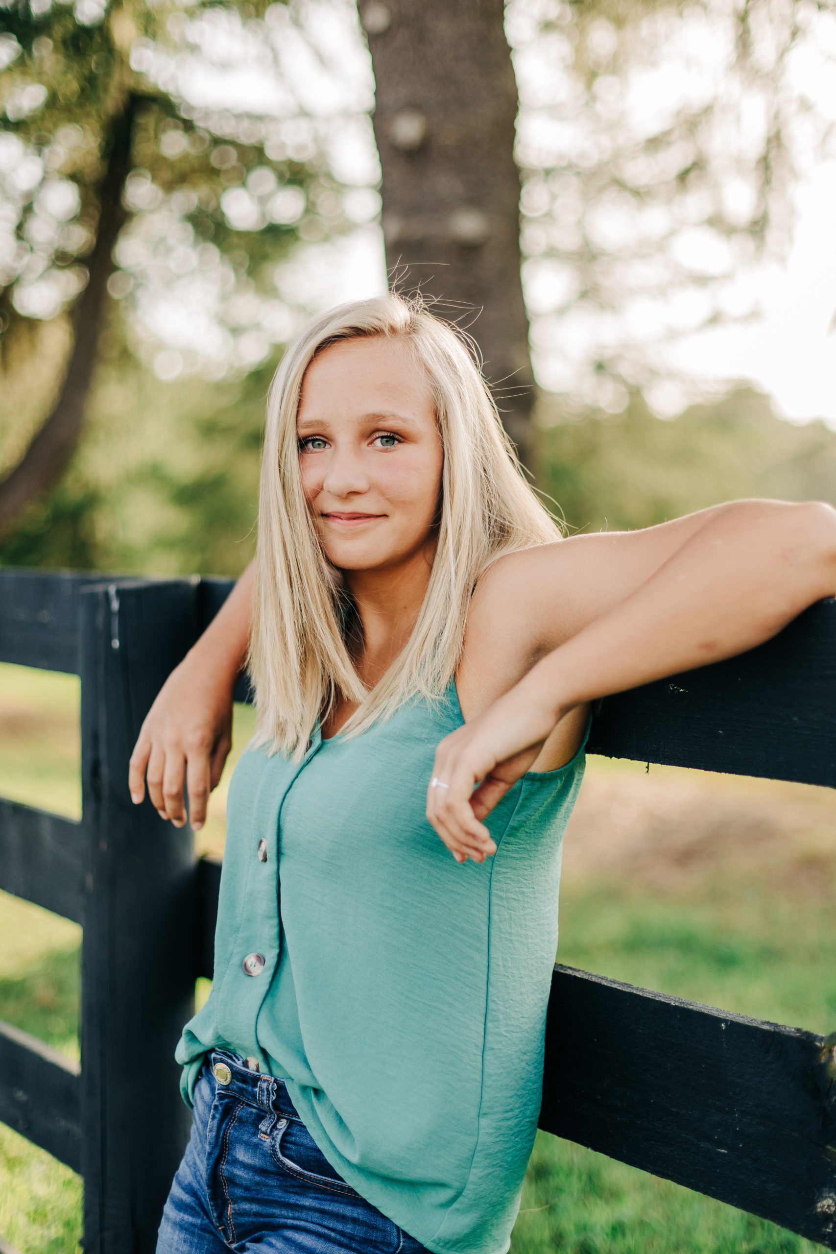 augusta photographer capture senior pictures with girl leaning on a fence on a farm