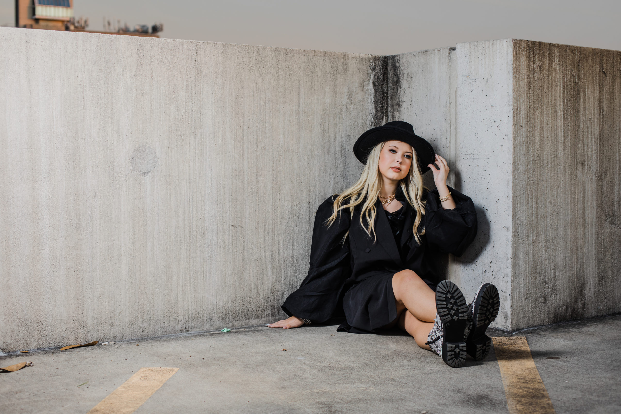 senior Augusta photographer photographs girl in all black sitting on top of a parking garage