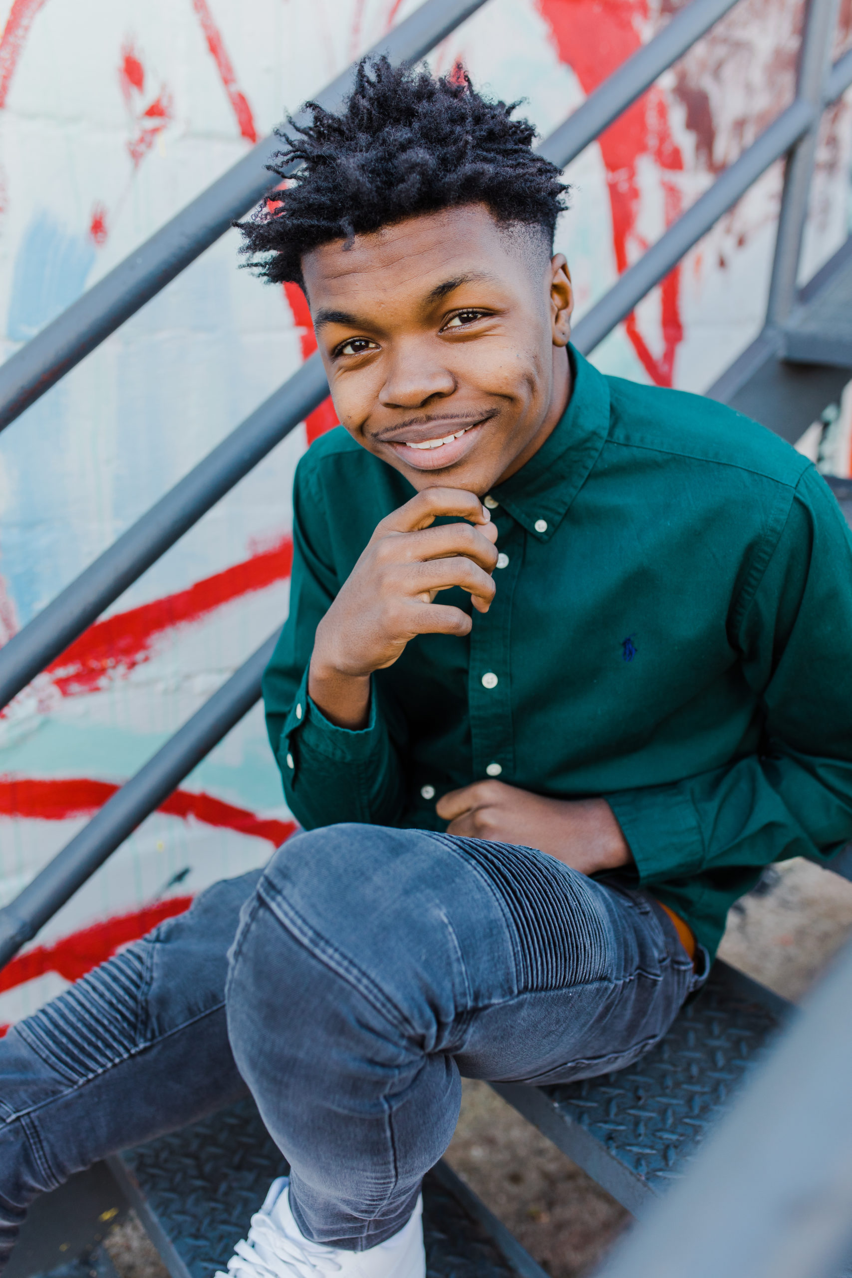 young man sits on stairs and poses for his senior session with augusta photographer