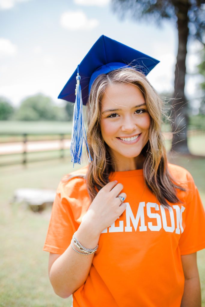 graduation pictures with high school senior wearing her blue cap and an orange school shirt