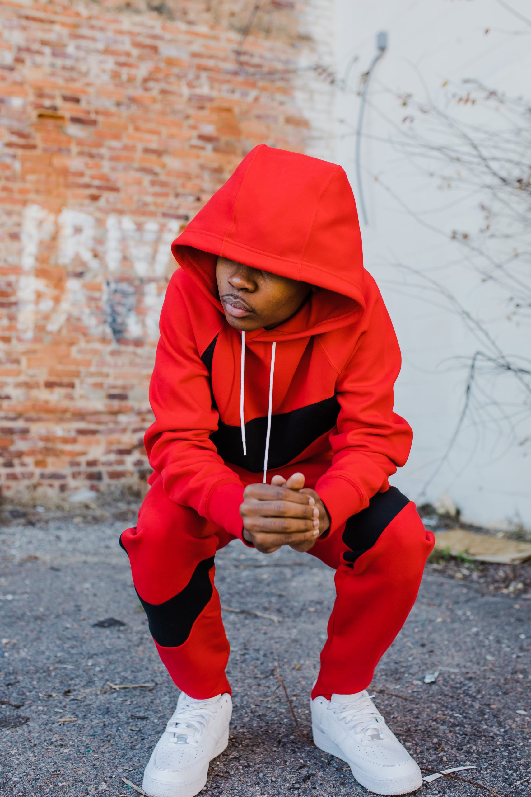 Augusta photographer captures boy in a red set crouching next to exposed brick
