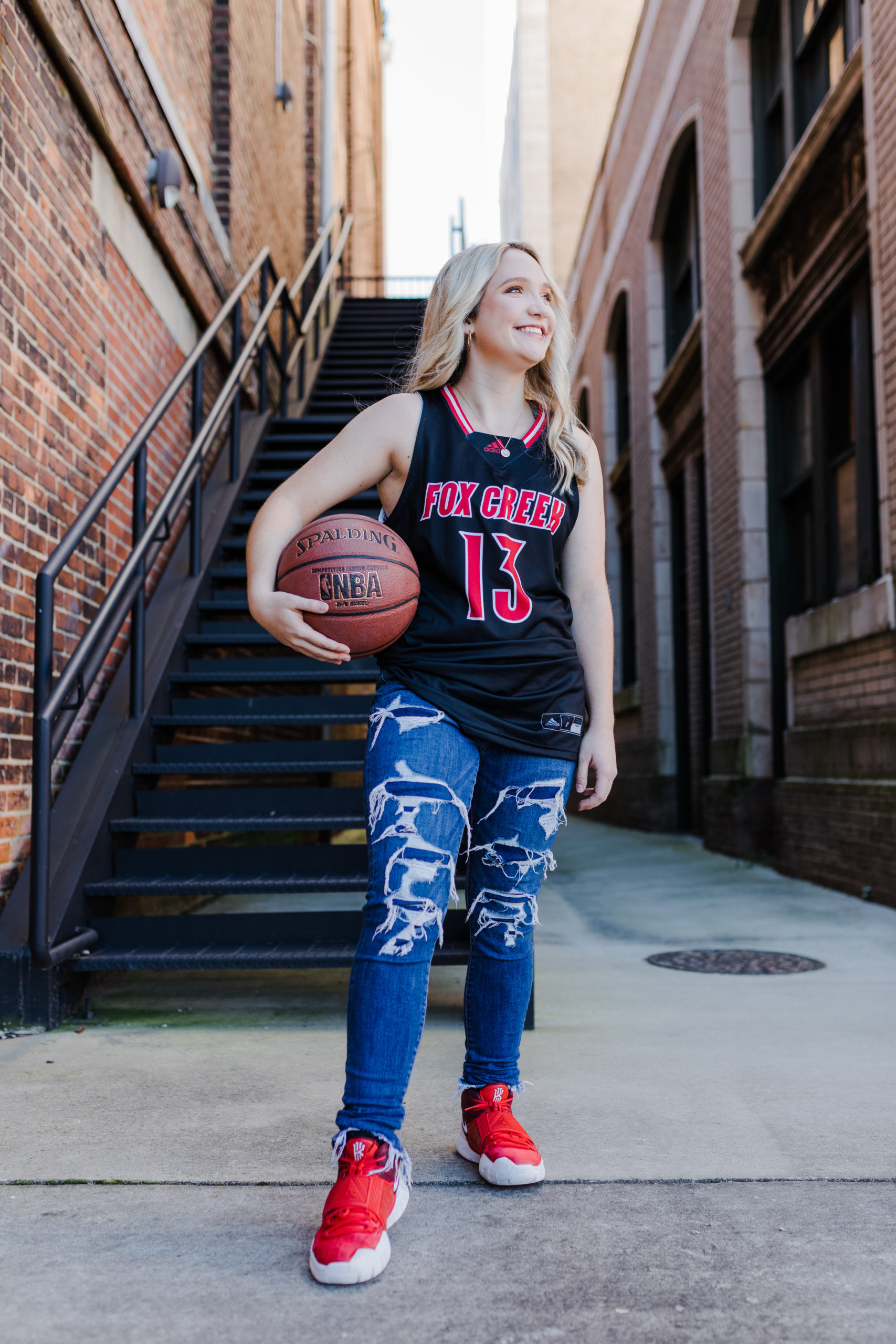 senio rpictures take by Augusta photographers with girl in a brick alley holding a basketball 