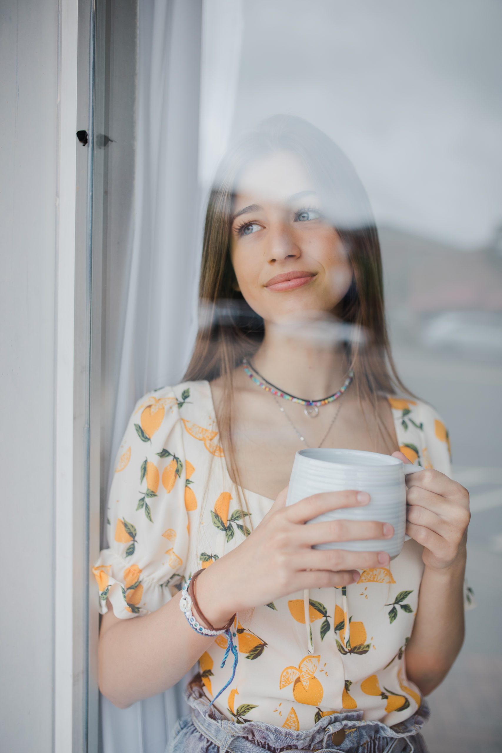 unique senior aesthetic with girl in a window holding her mug as she looks out