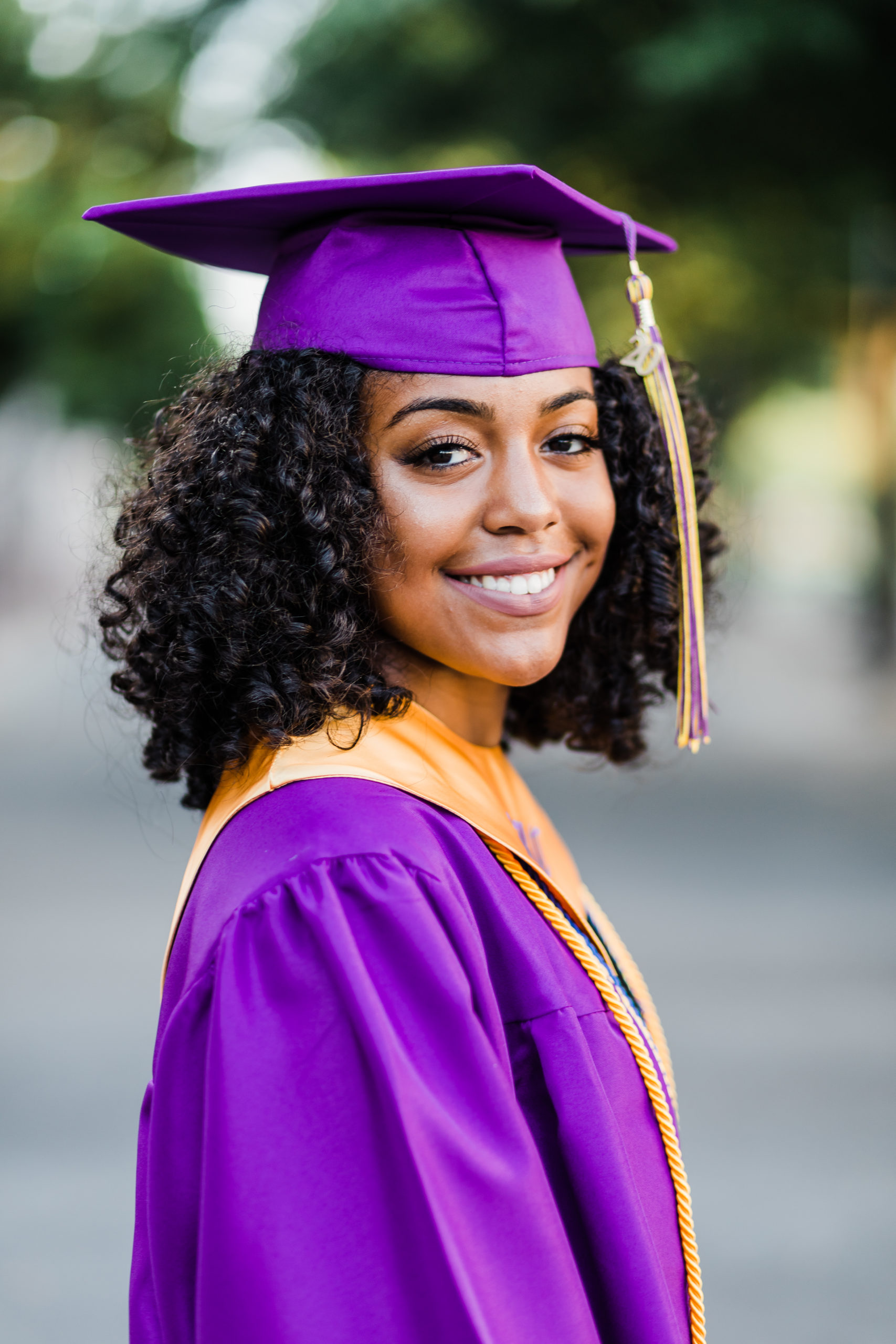 cap and gown picture with girl in prurple smiling over her shoulder