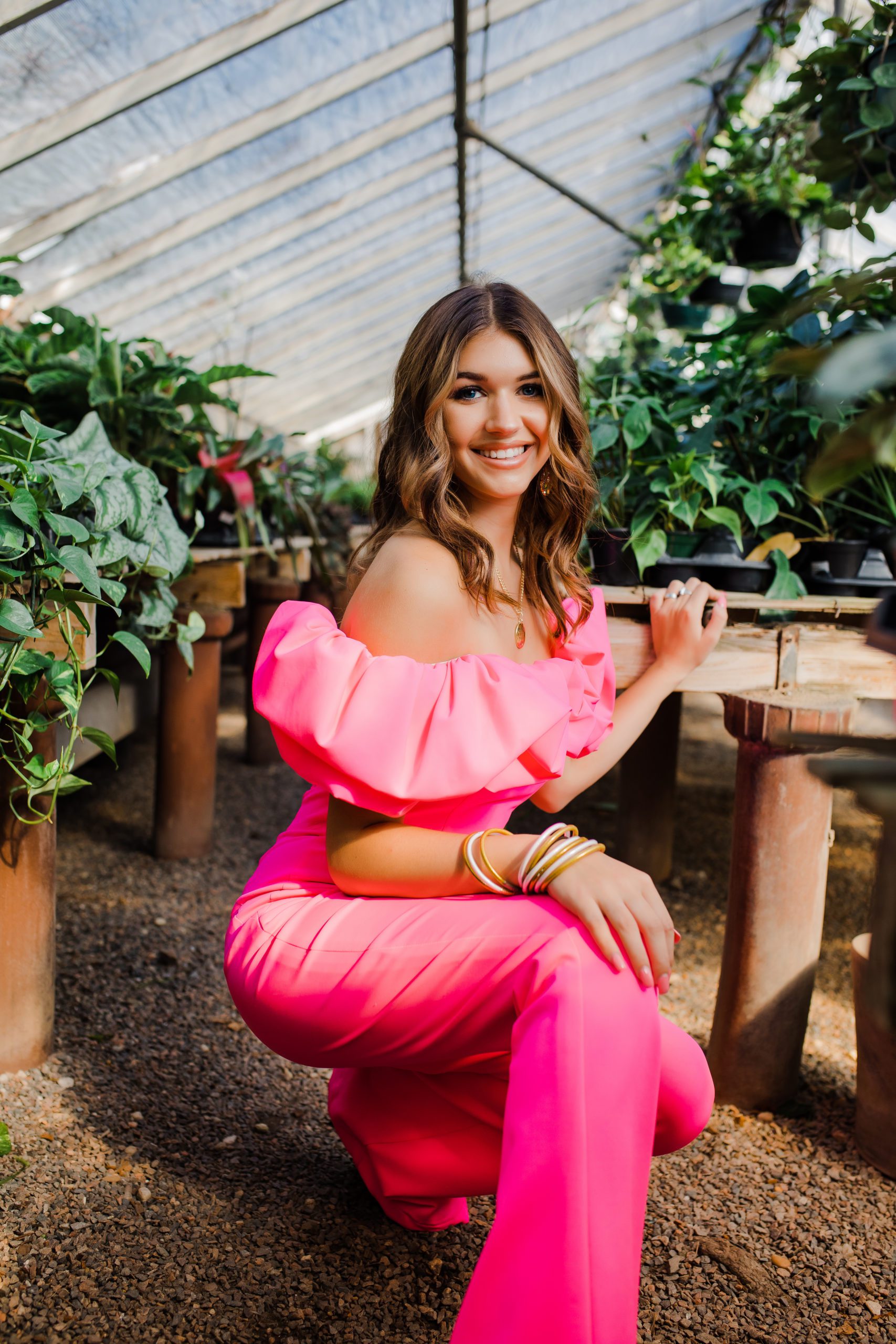 Augusta photographer captures senior pictures with girl in a hot pink outfit posing in a green house