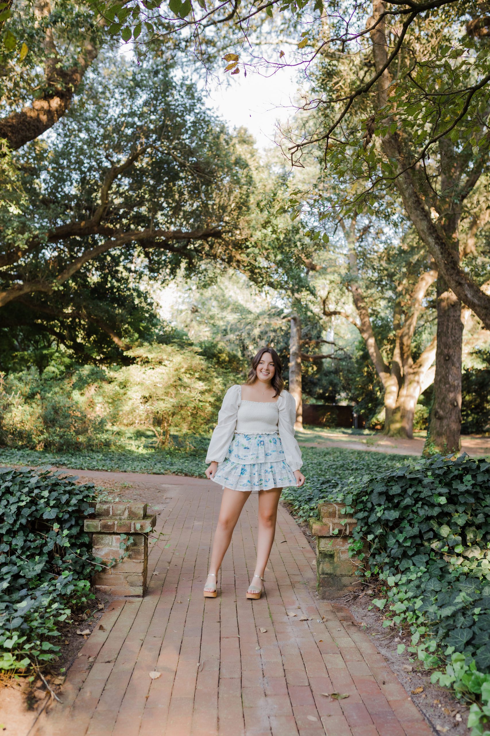 senior photos with girl standing in a garden wearing a blue florals skirt photographed by Augusta photographer