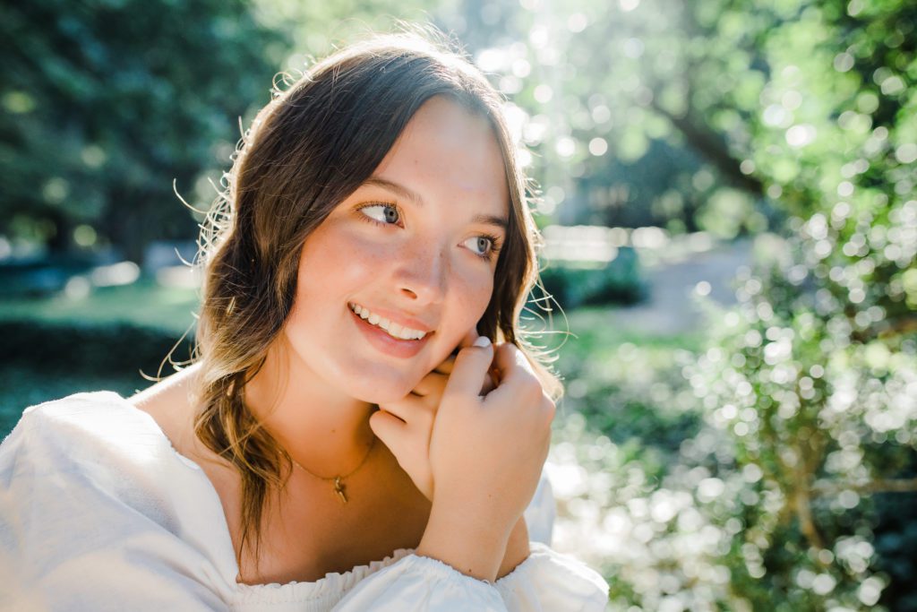 outdoor senior pictures with girl in a garden wearing a white blouse taken by Augusta photographer 
